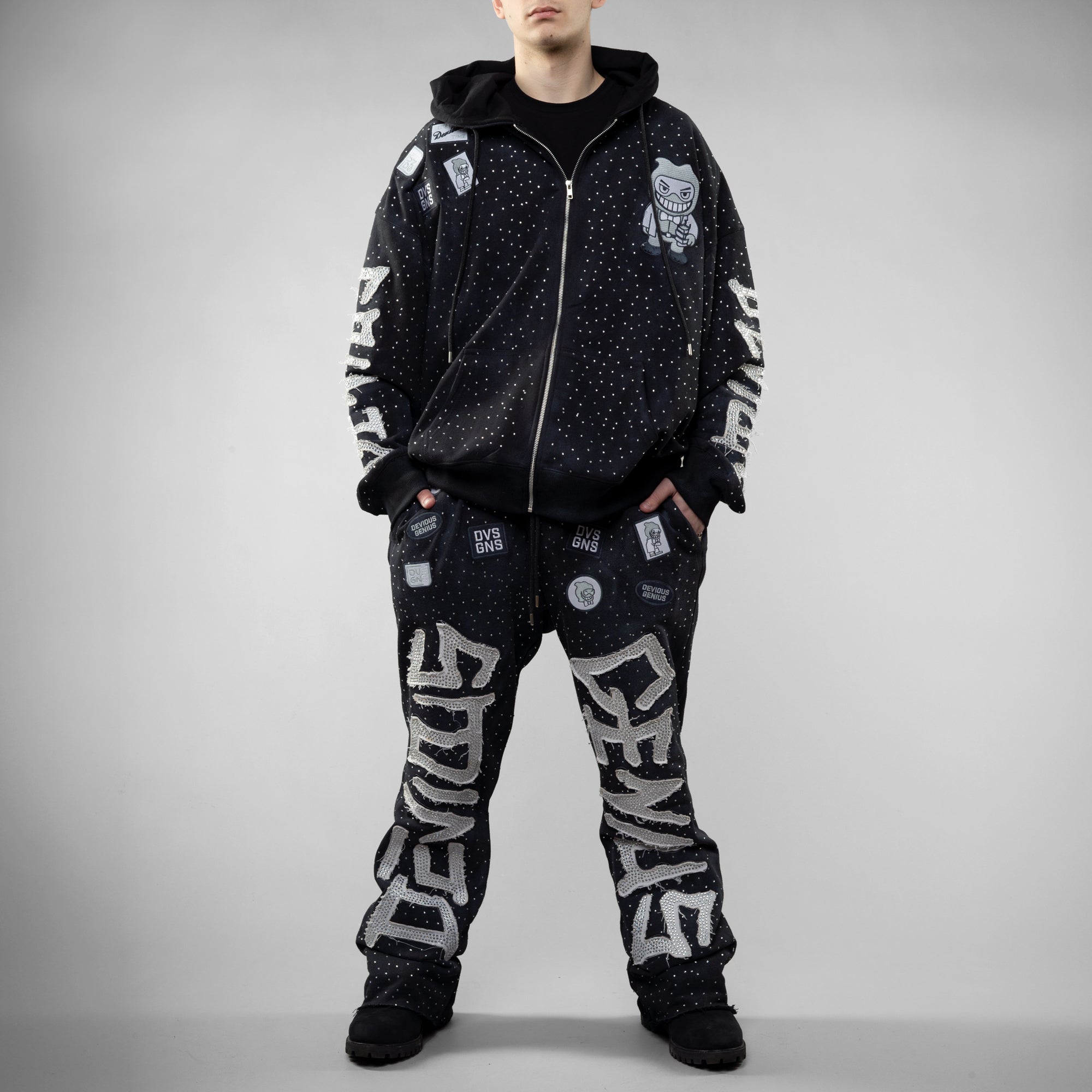 Person wearing a black tracksuit with white text and graphics on a gray background