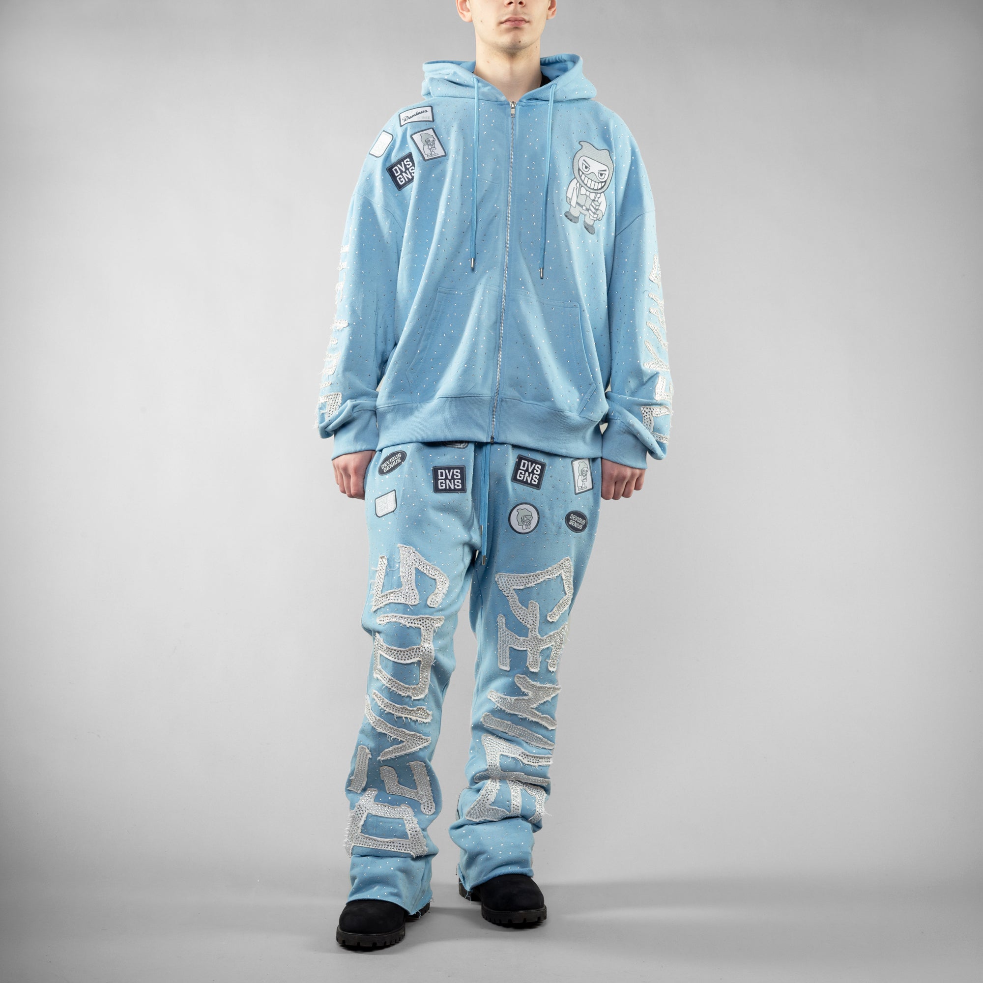 Person wearing a blue tracksuit with patches and text on a gray background