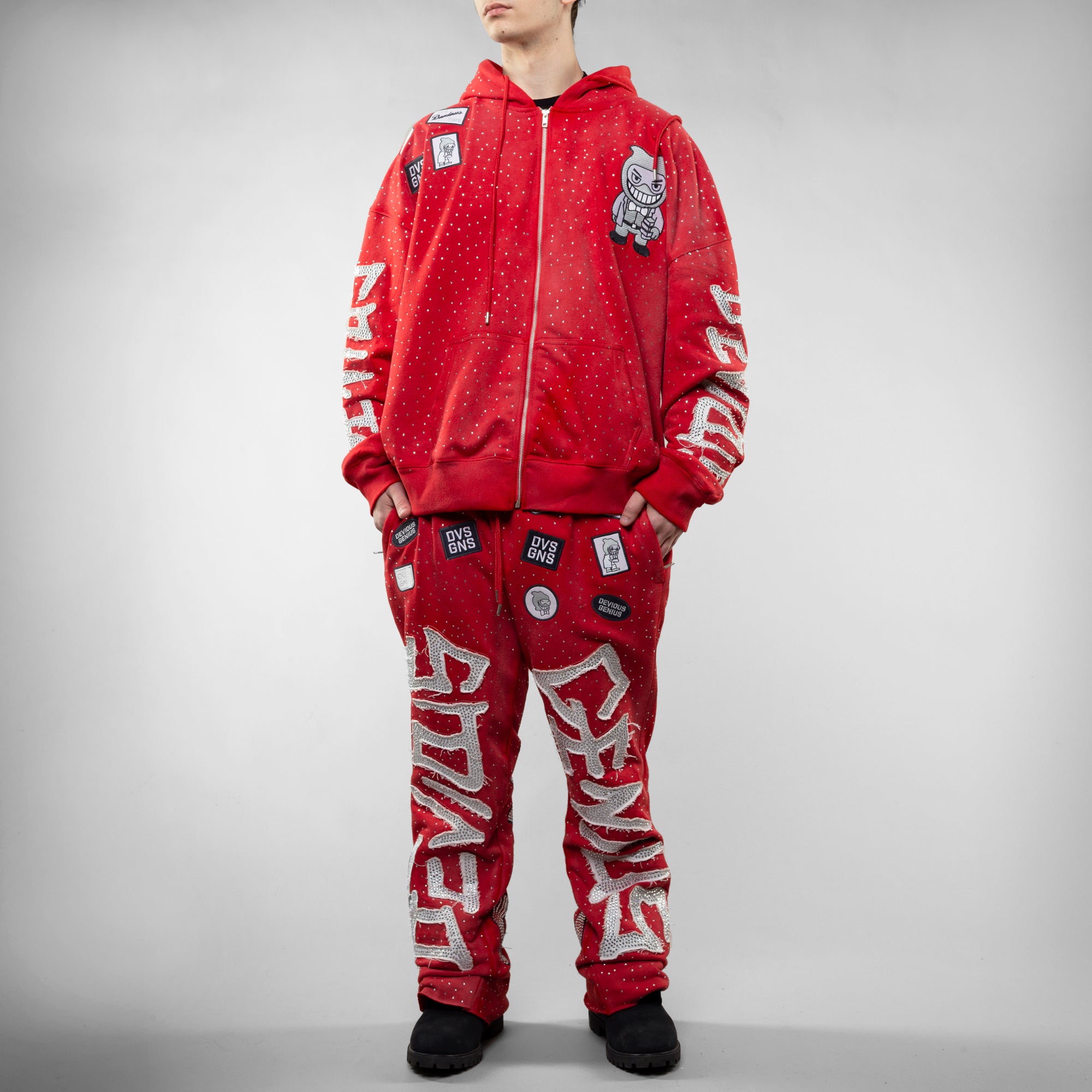 Person wearing a red tracksuit with white text and logos on a gray background